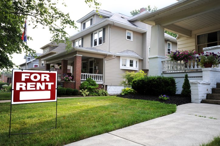 A house with a "For Rent" sign on the front lawn.